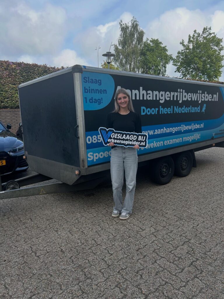 Geslaagde cursist staat met bord voor een aanhanger na het behalen van het BE-rijbewijs in Utrecht.